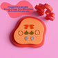 A jewelry charm display set on a pink background, featuring a peach and coral display tray with three pairs of charms (orange, green, and blue), two red 3D charm pieces, and blue text explaining the included styles.